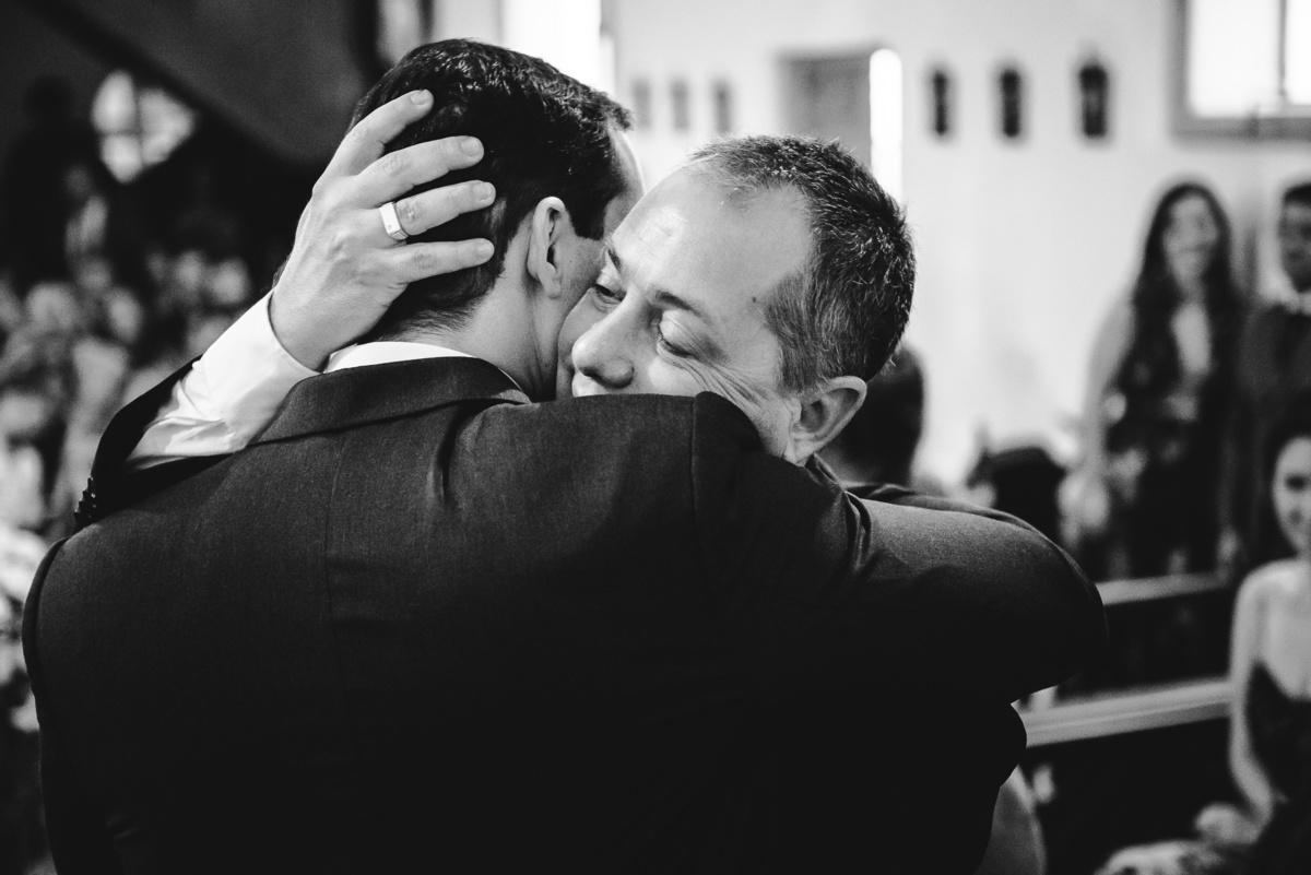 O pai da noiva Luana abraçando o noivo Julio após a celebração do casamento na Capela Santa Ignez, Gávea, Rio de Janeiro-RJ