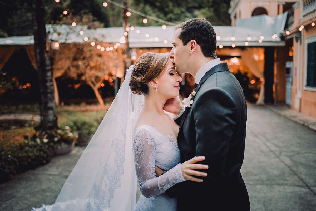 O noivo Julio beijando a testa de sua esposa Luana no ensaio após a celebração do casamento e antes da entrada na festa, Capela Santa Ignez, Gávea, Rio de Janeiro-RJ.