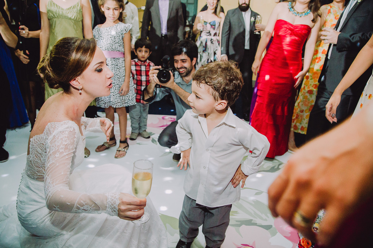 João Paulo, sobrinho dos noivos Luana e Julio, com as mãos na cintura conversando a noiva na pista de dança da festa de casamento no salão da Capela Santa Ignez, Gávea, Rio de Janeiro-RJ.