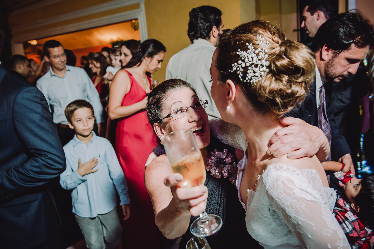 Convidada da festa muito animada com uma taça de prosecco na mão falando com a noiva na festa do casamento  de Luana e Julio no salão da Capela Santa Ignez, Gávea, Rio de Janeiro-RJ.