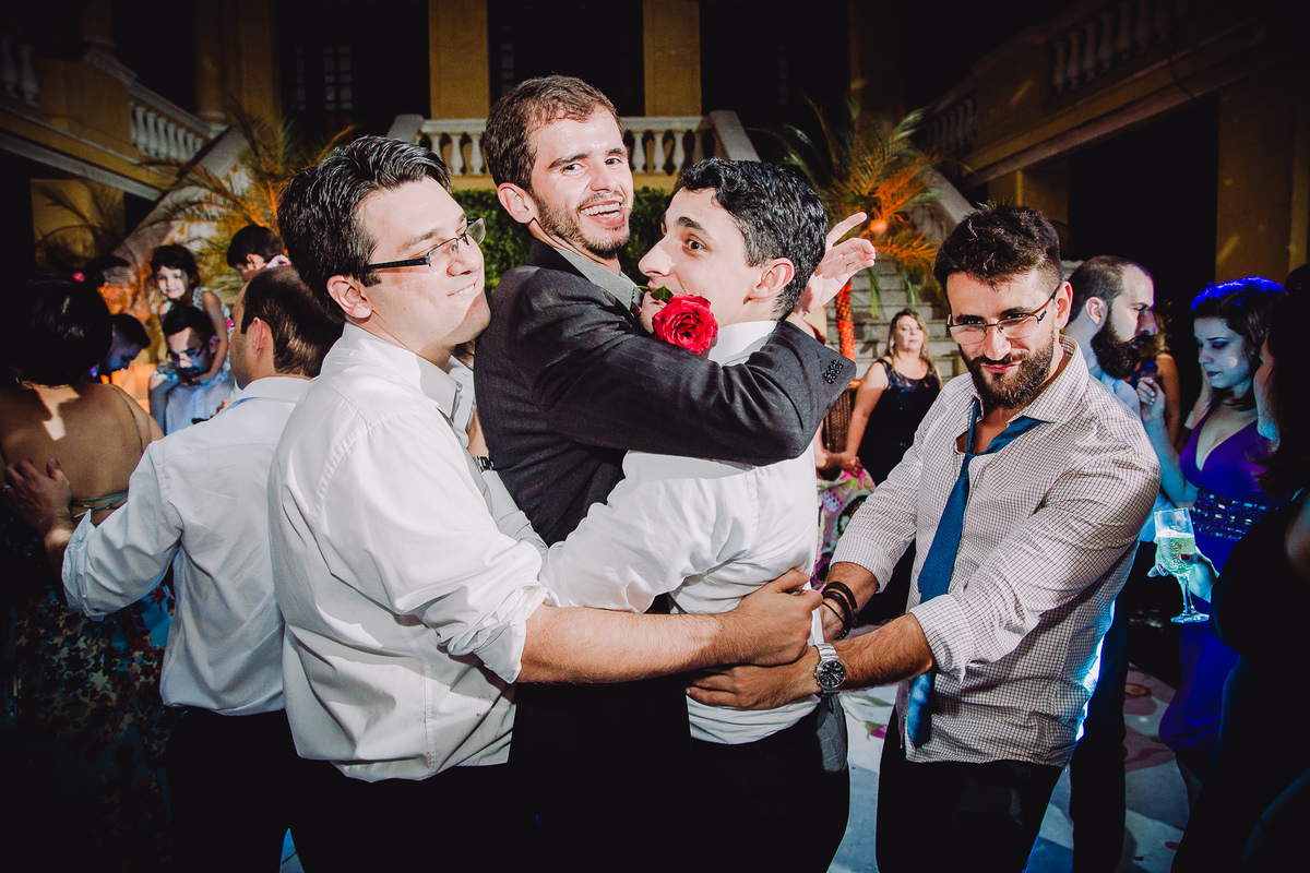 Padrinho com uma rosa vermelha na boca fazendo muita zoeira na pista de dança do casamento de Luana e Julio no salão da Capela Santa Ignez, Gávea, Rio de Janeiro-RJ.