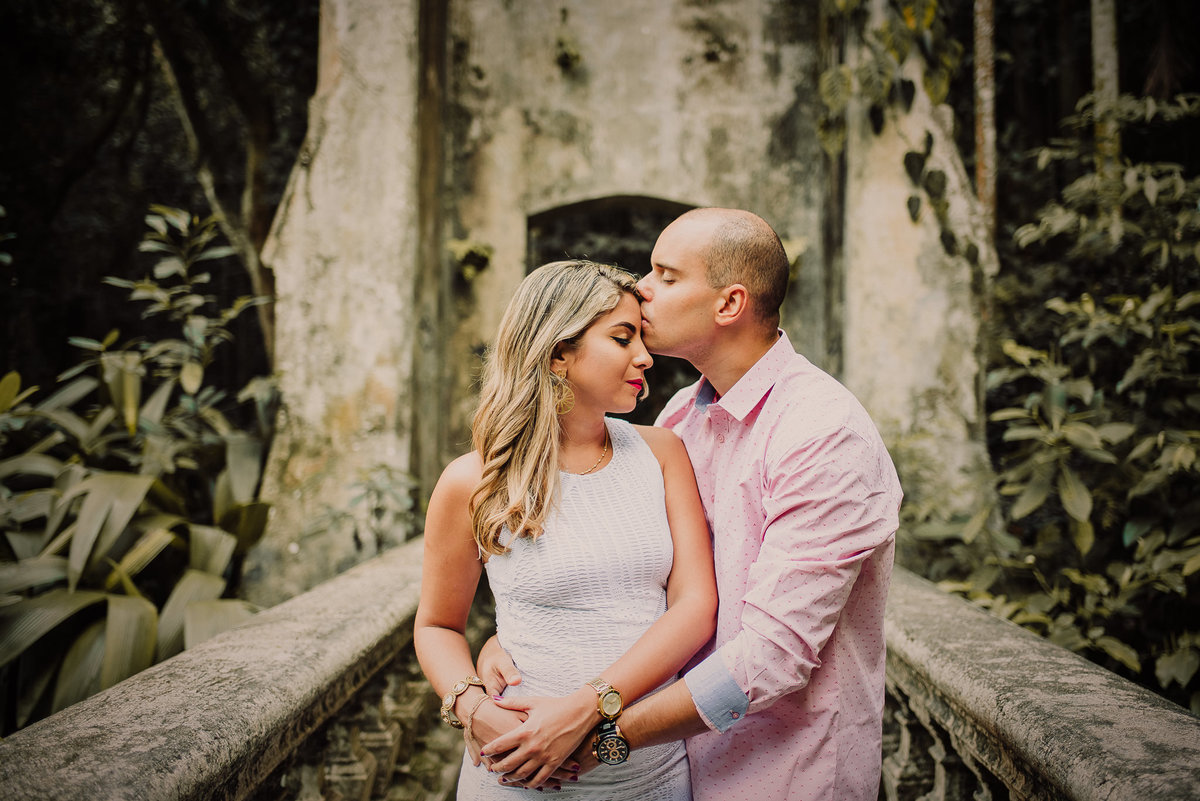 O noivo Bryan beijando a testa da sua noiva Naira num lindo momento do ensaio pré-casamento no Parque Lage, Rio de Janeiro-RJ