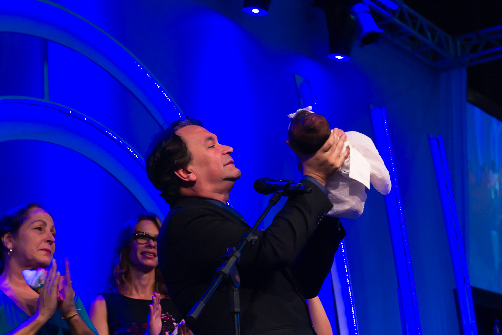 Pastor Simonton Ergue a criança e declara que É de Deus na Igreja Missão Praia da Costa pelo fotógrafo Douglas Maia