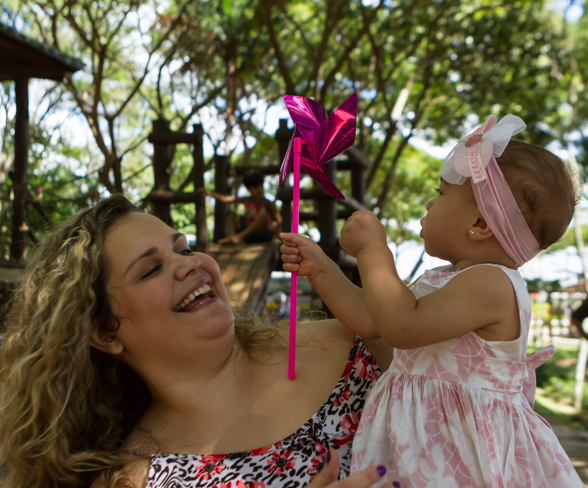 Luísa se diverte com catavento no colo da mãe pelo fotógrafo Douglas Maia