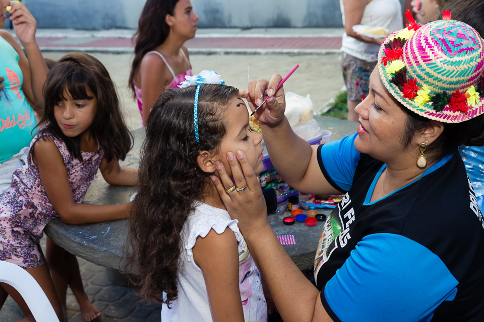Menina recebendo pintura no rosto pelo fotógrafo Douglas Maia