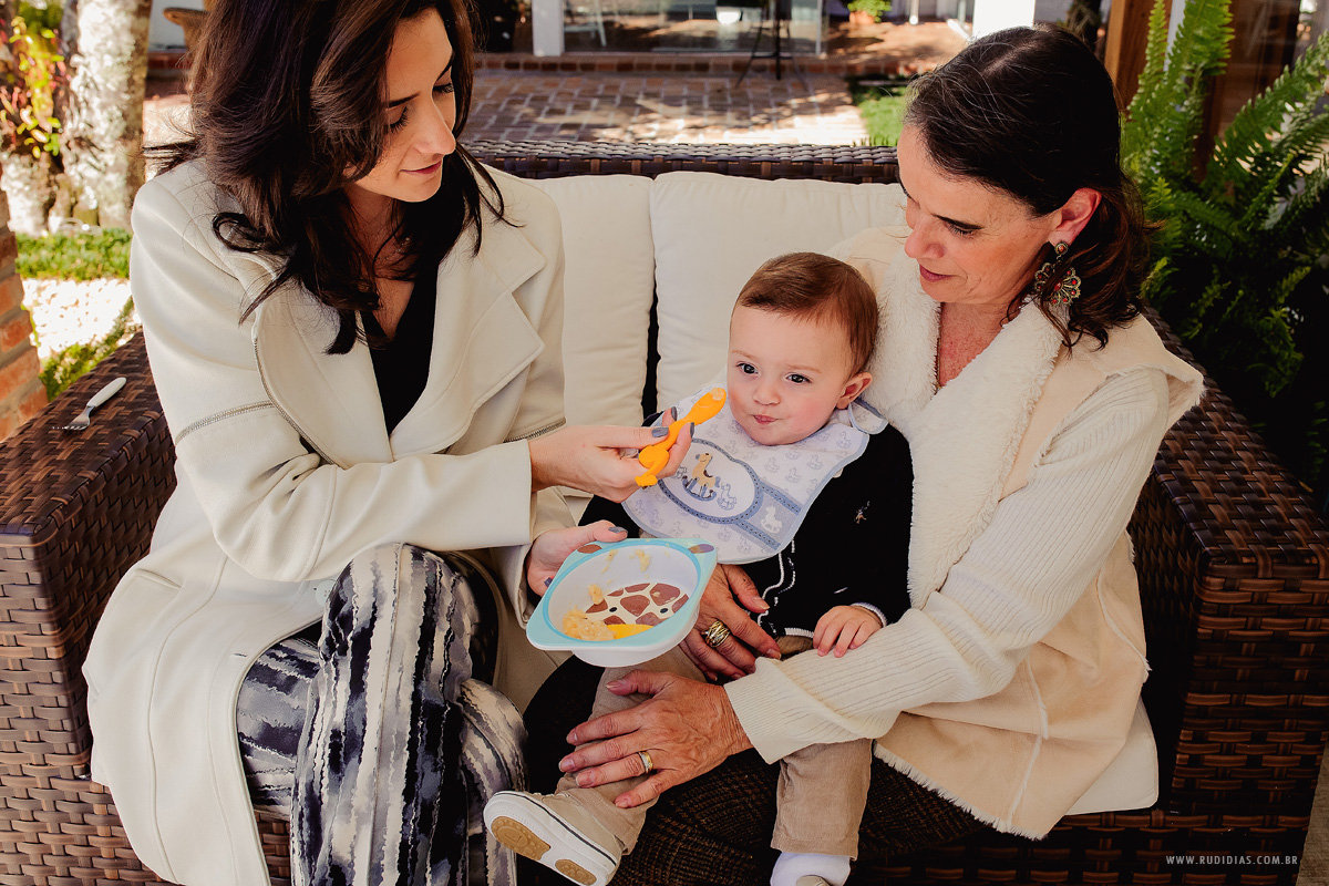 mãe dando papinho pro filho no batizado