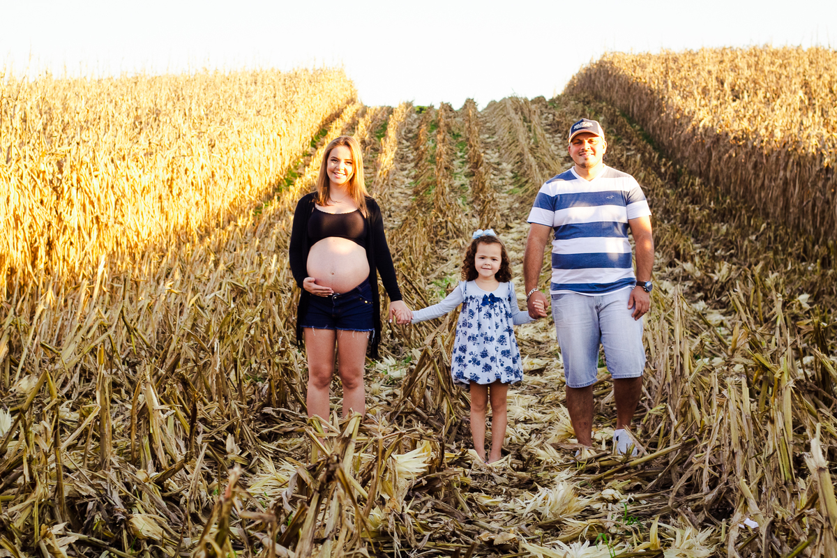 foto no milharal da grávida, com sua filha e seu marido, ensaio fotográfico ao ar livre, feito pela fotografa Aline Paim 