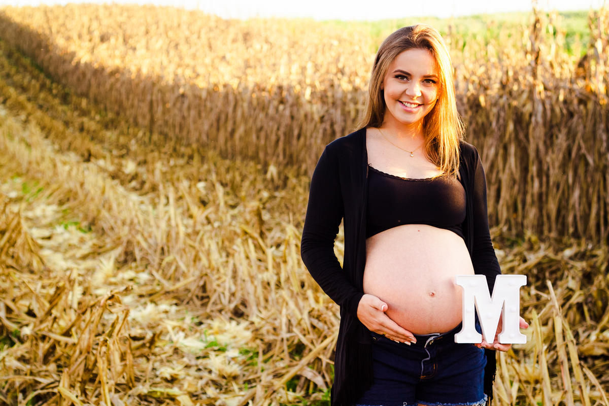 gestante sendo fotografada por Aline Paim ao ar livre no meio de um milharal