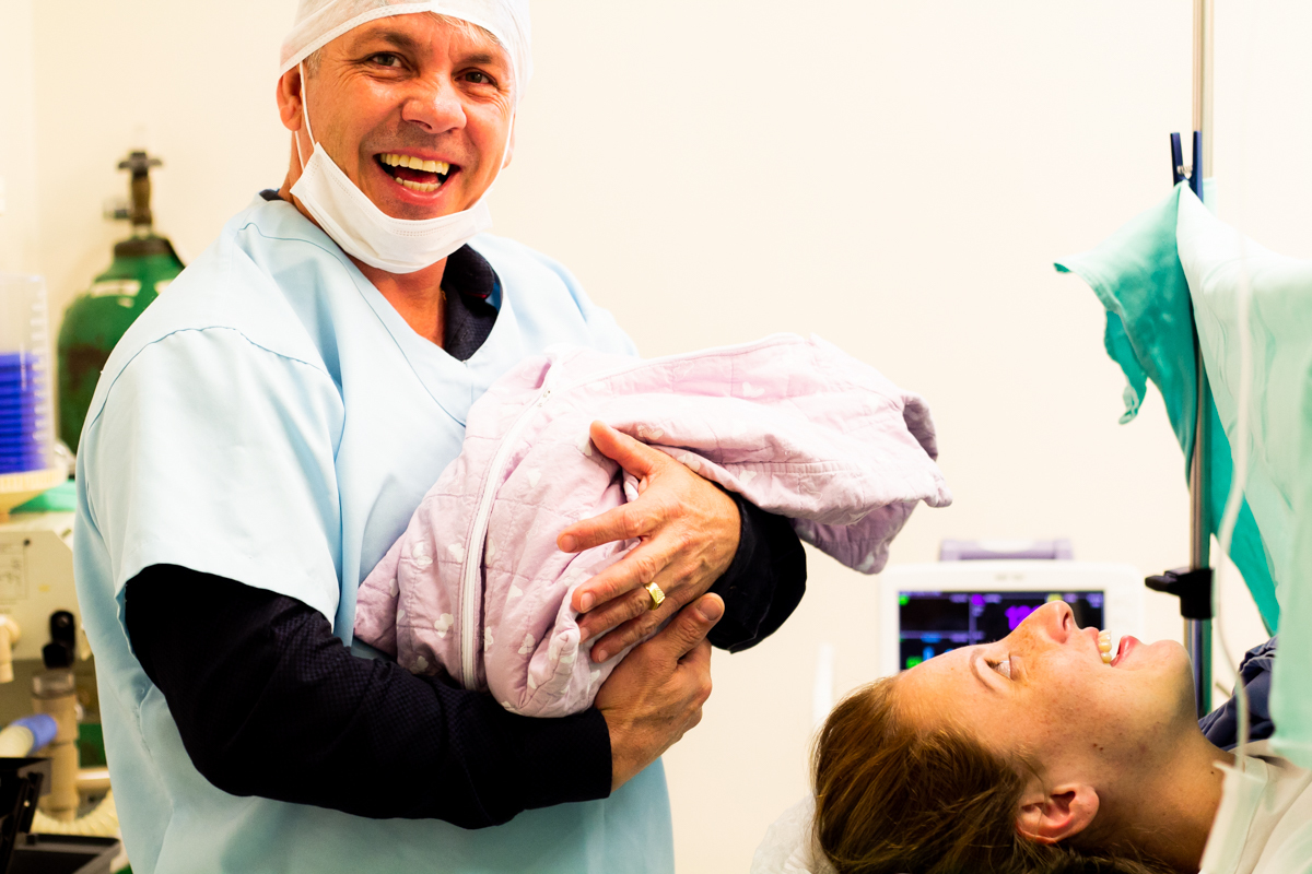 sorriso largo do papai da bebê Maria Laura logo após o seu nascimento, foto linda do parto feita pela Aline Paim