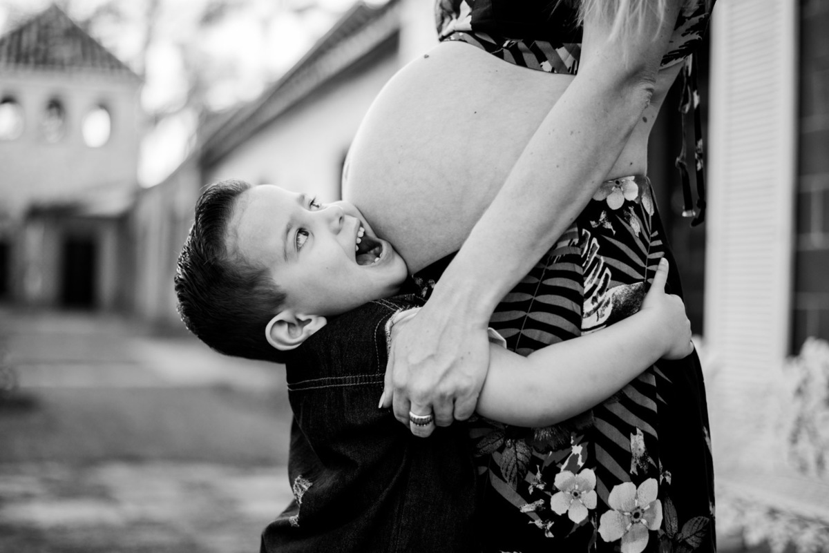 criança beijando barriga da mãe 