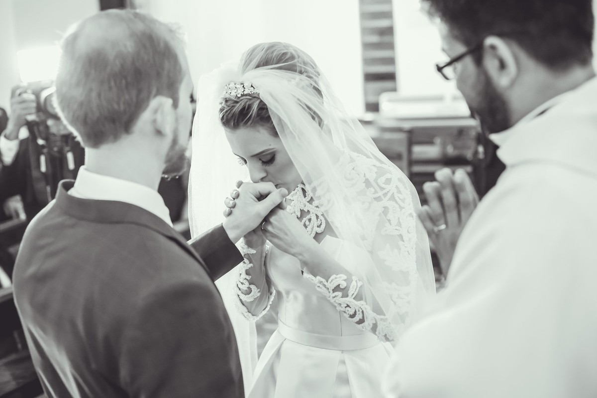 noiva beijando a mao do noivo ja com alianca foto tirada nas lentes do fotografo thiago alt