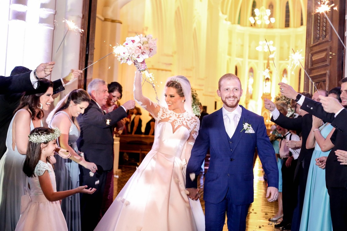 noivos saindo da igreja e noiva com seu buque na mao foto tirada nas lentes do fotografo thiago alt