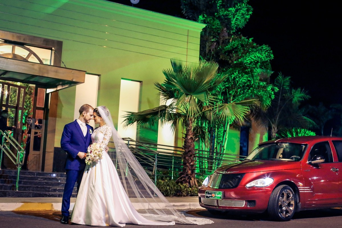 noivos olhando um pro outro ao lado o carro foto tirada nas lentes do fotografo thiago alt