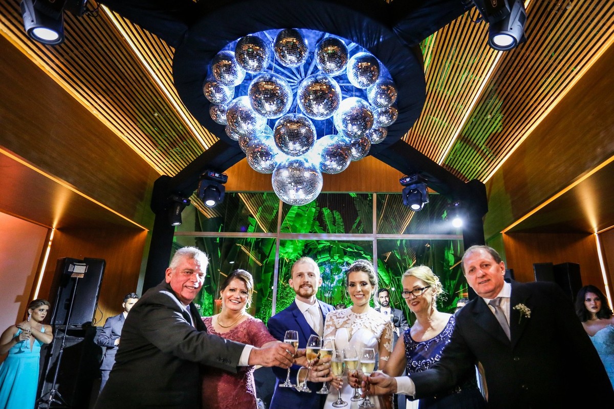 noivos acompanhados dos seus pais com as suas tacas em maos foto tirada nas lentes do fotografo thiago alt