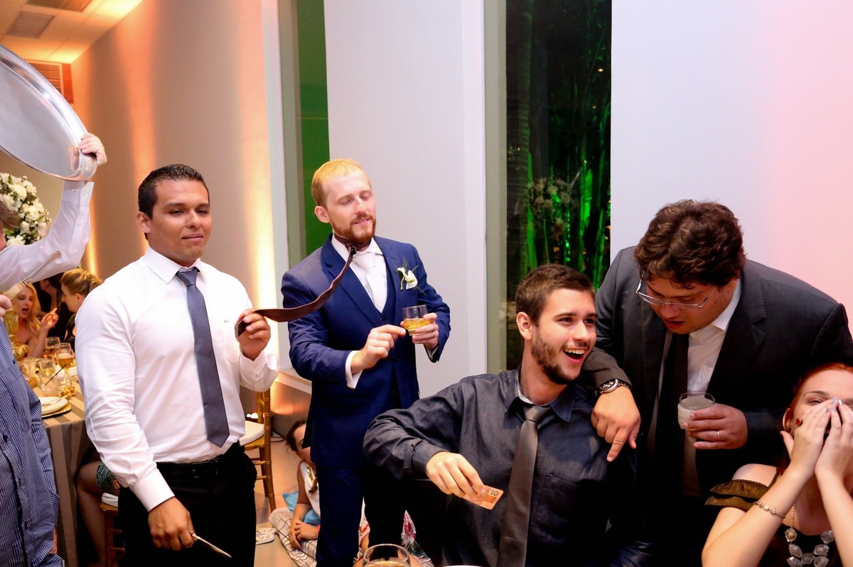 noivo com seus padrinhos e convidados cortado sua gravata para a lua de mel foto tirada nas lentes do fotografo thiago alt