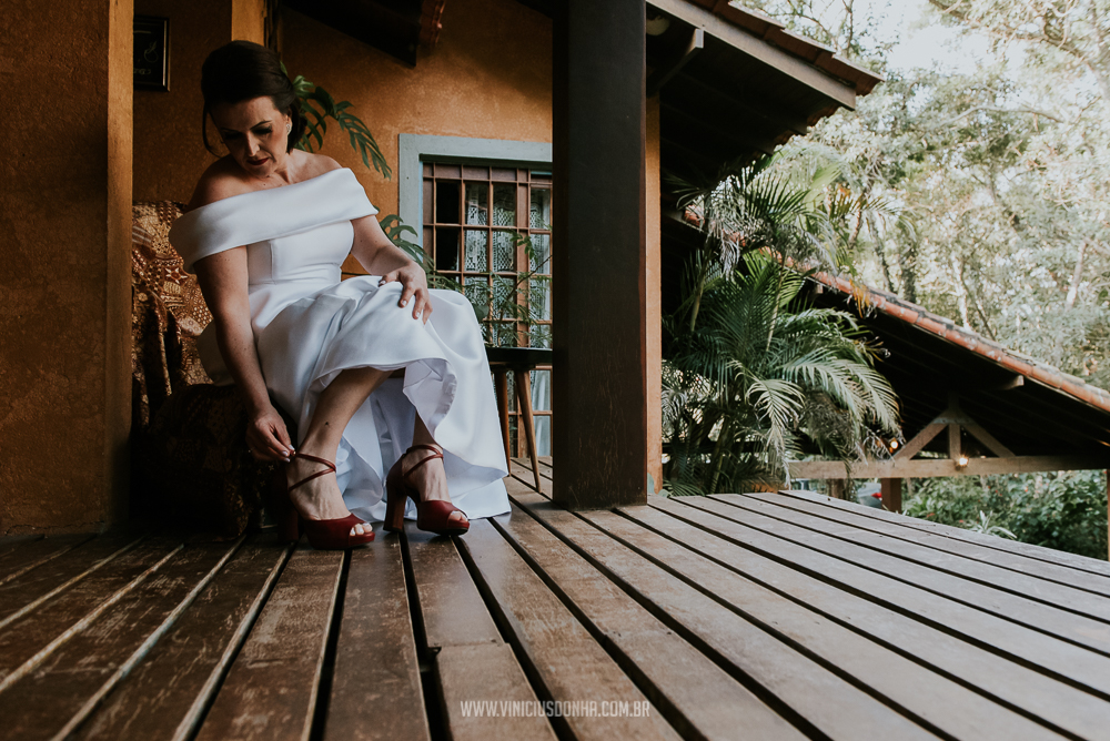 Noiva com seu vestido de noiva arrumando seu sapato de noiva no espaço Estação Gaia, por fotógrafo de casamento, Vinicius Donha