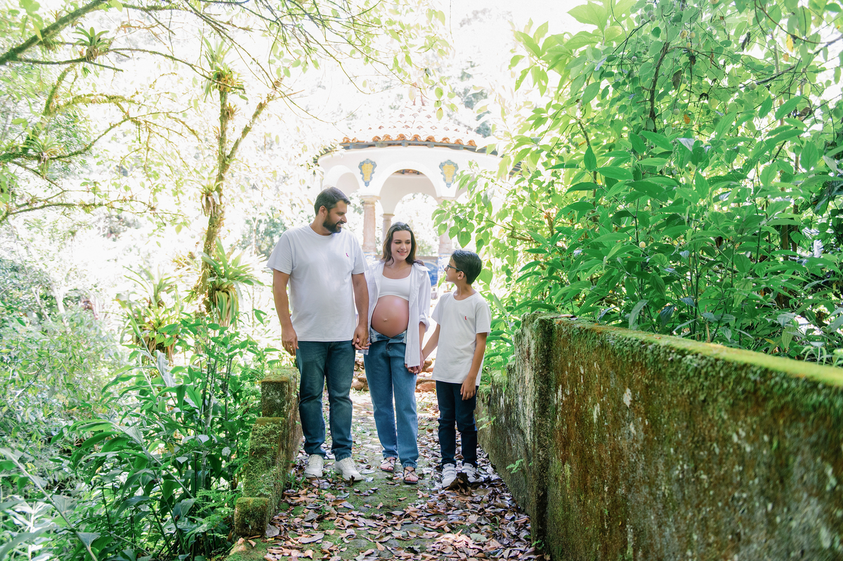 Família parada em caminho arborizado durante ensaio gestante externo com área verde na serra do RJ