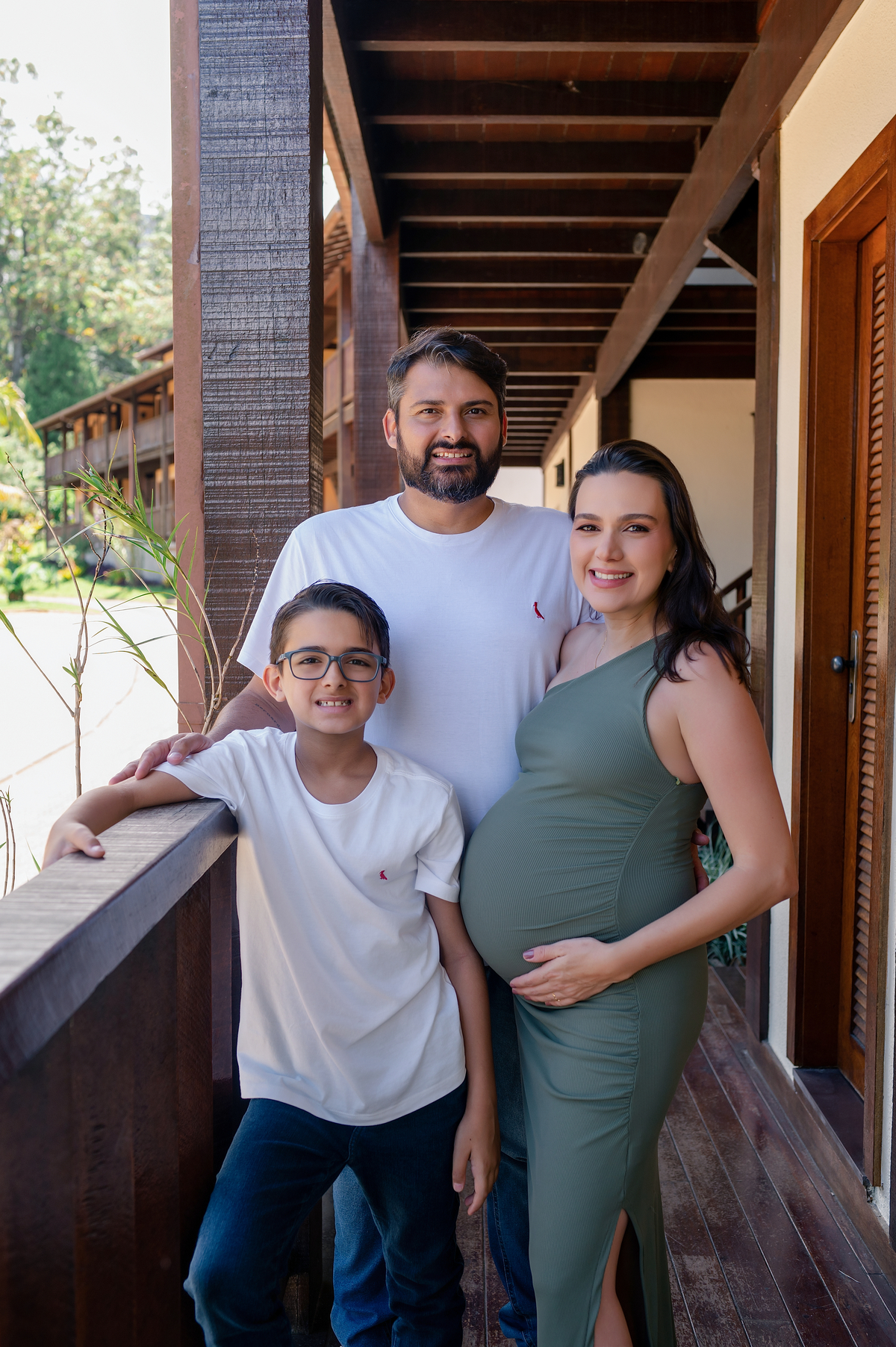 Família sorrindo na varanda de madeira dos quartos da Pousada Terê Parque