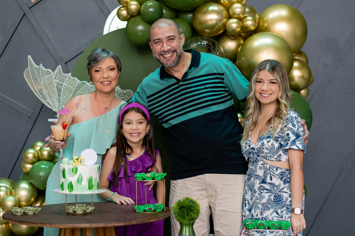 Andrea com marido e as filhas para retrato na mesa do bolo