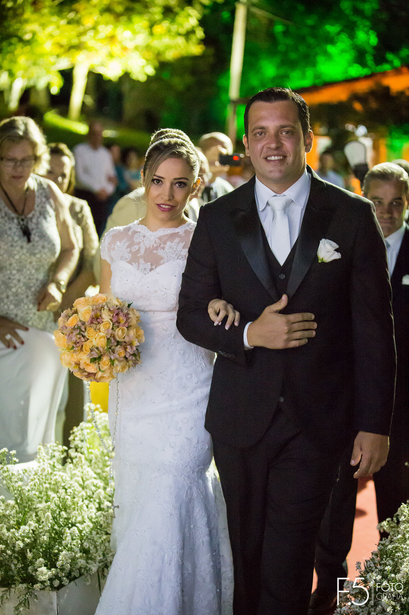 Noivos Lívia e Renato, entrando de braços dados para a cerimônia que aconteceu em Muzambinho - MG.