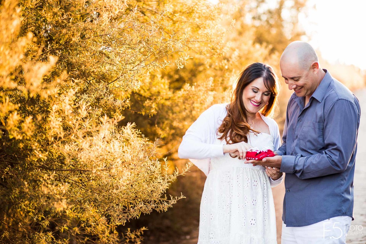 Gestante e esposo segurando sapatinho do bebê, Ensaio Gestante Poços de Caldas - MG