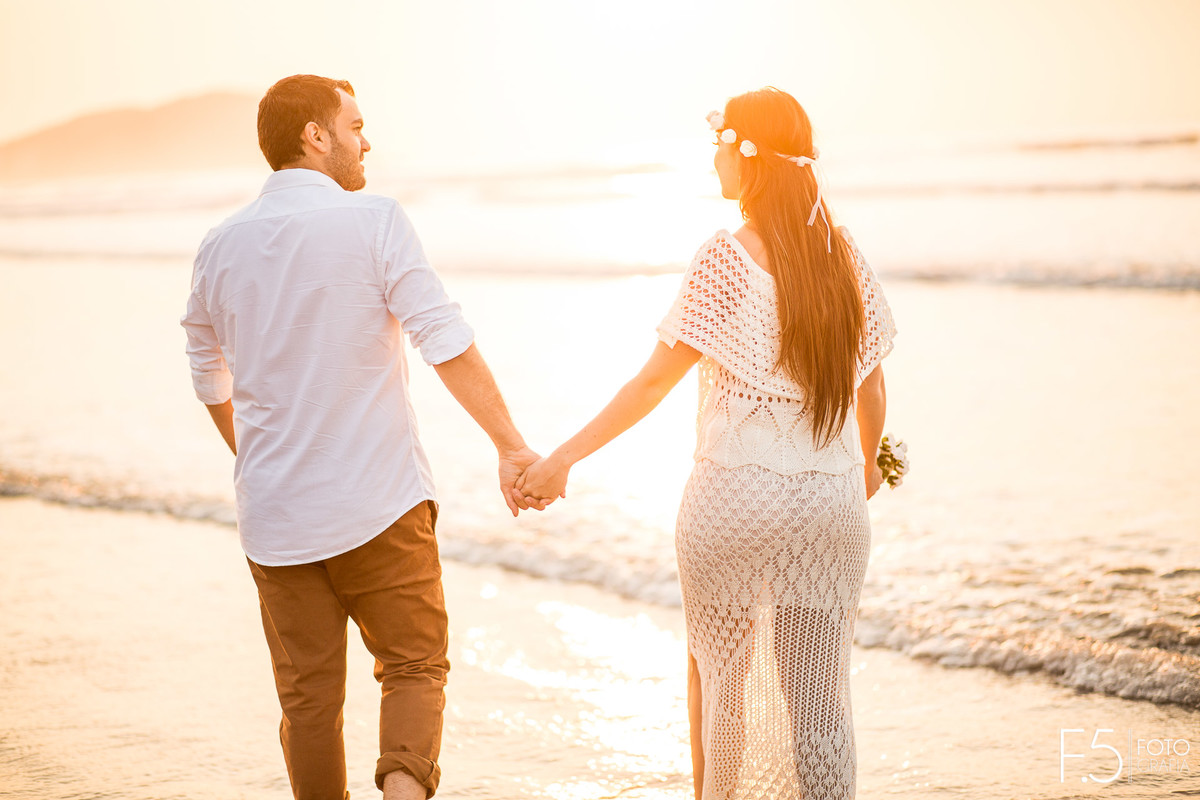 Noivos de mão dadas em meio a praia Casal de noivos correndo na praia Pré Wedding - Praia Riviera de São Lourenço