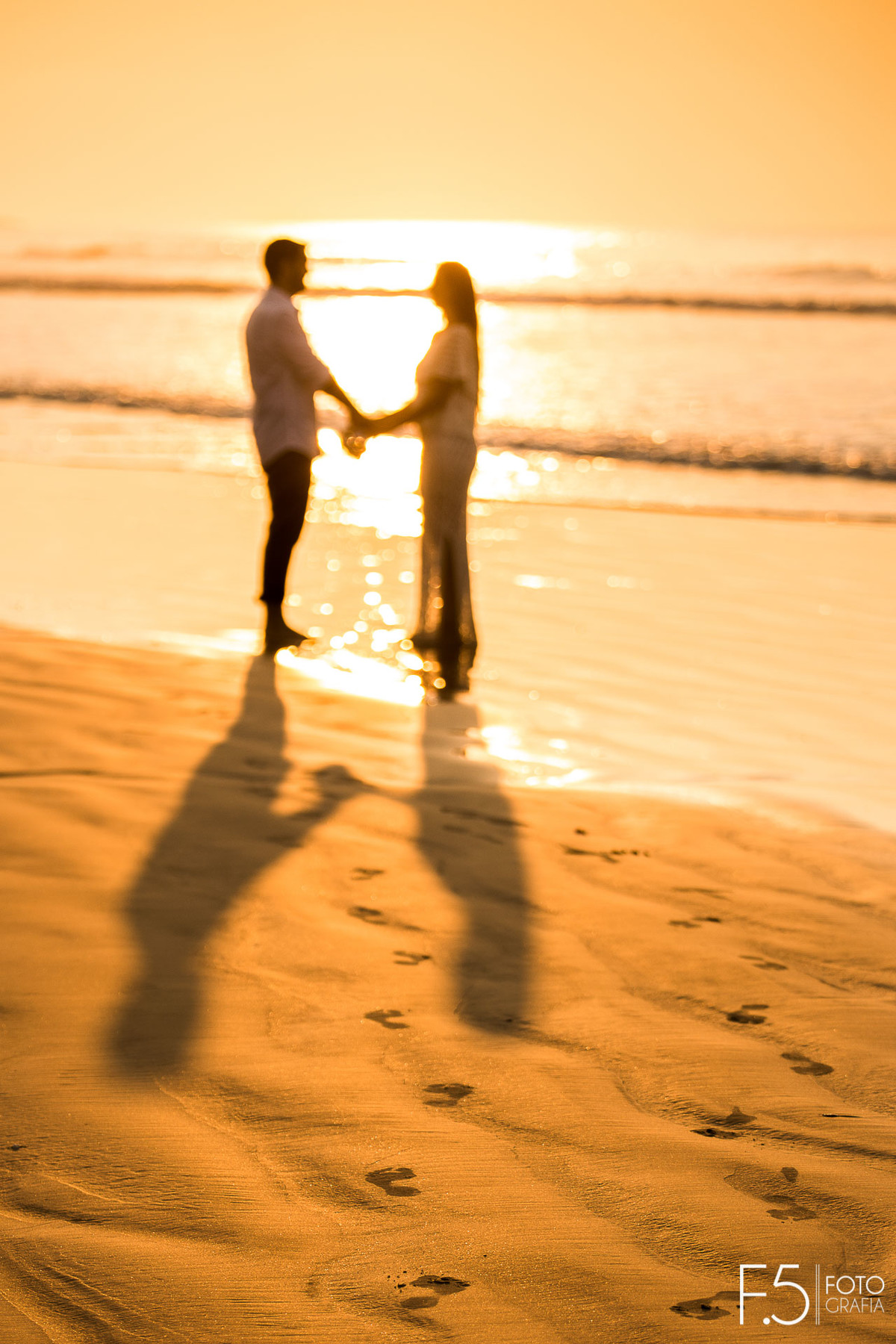 Noivos de olhando em meio ao pôr do sol Casal de noivos correndo na praia Pré Wedding - Praia Riviera de São Lourenço
