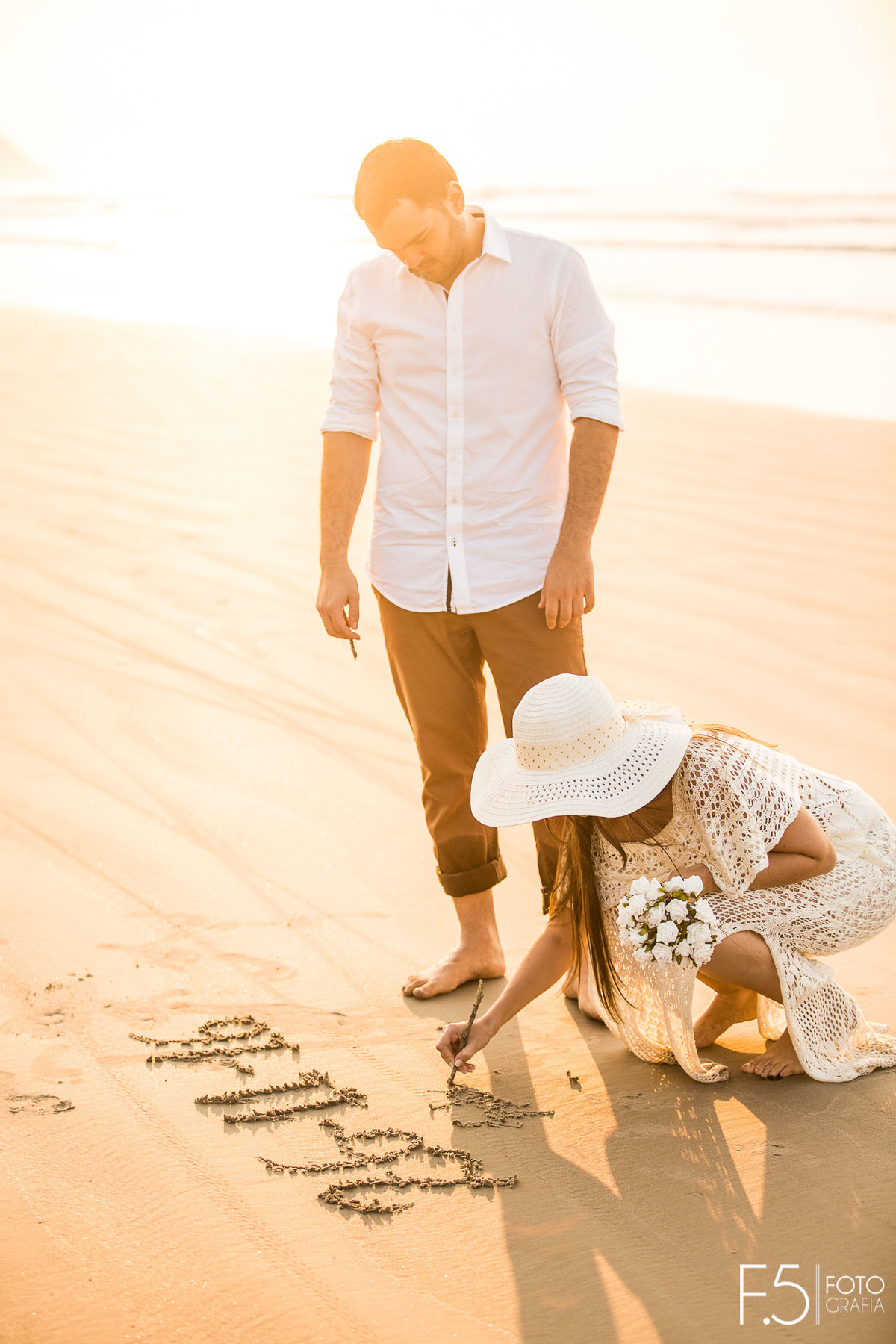 Noiva escrevendo na areia da praia Casal de noivos correndo na praia Pré Wedding - Praia Riviera de São Lourenço
