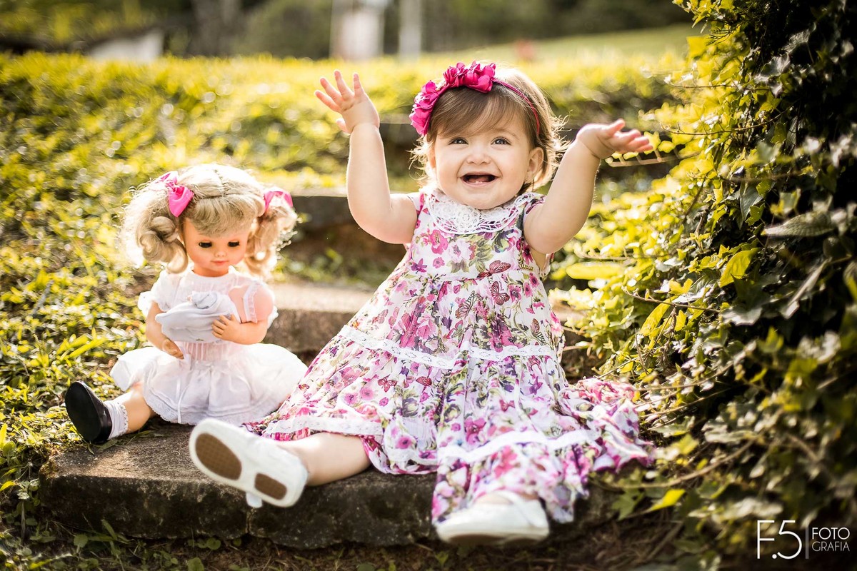 Mariana, sentada em uma escada ao lado de sua boneca, em Muzambinho - MG.
