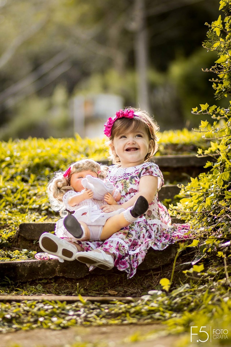 Mariana, sentada em uma escada com sua boneca no colo, em Muzambinho - MG.