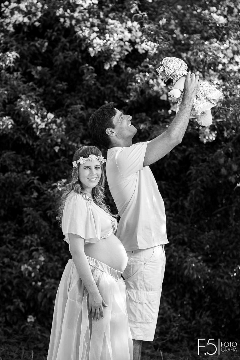 Gabriela e Eduardo, em meio a um jardim segurando uma boneca, em Cabo Verde - MG