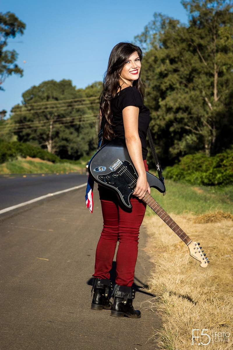 Bruna, rockeira segurando a guitarra em meio a estrada, em Muzambinho - MG.