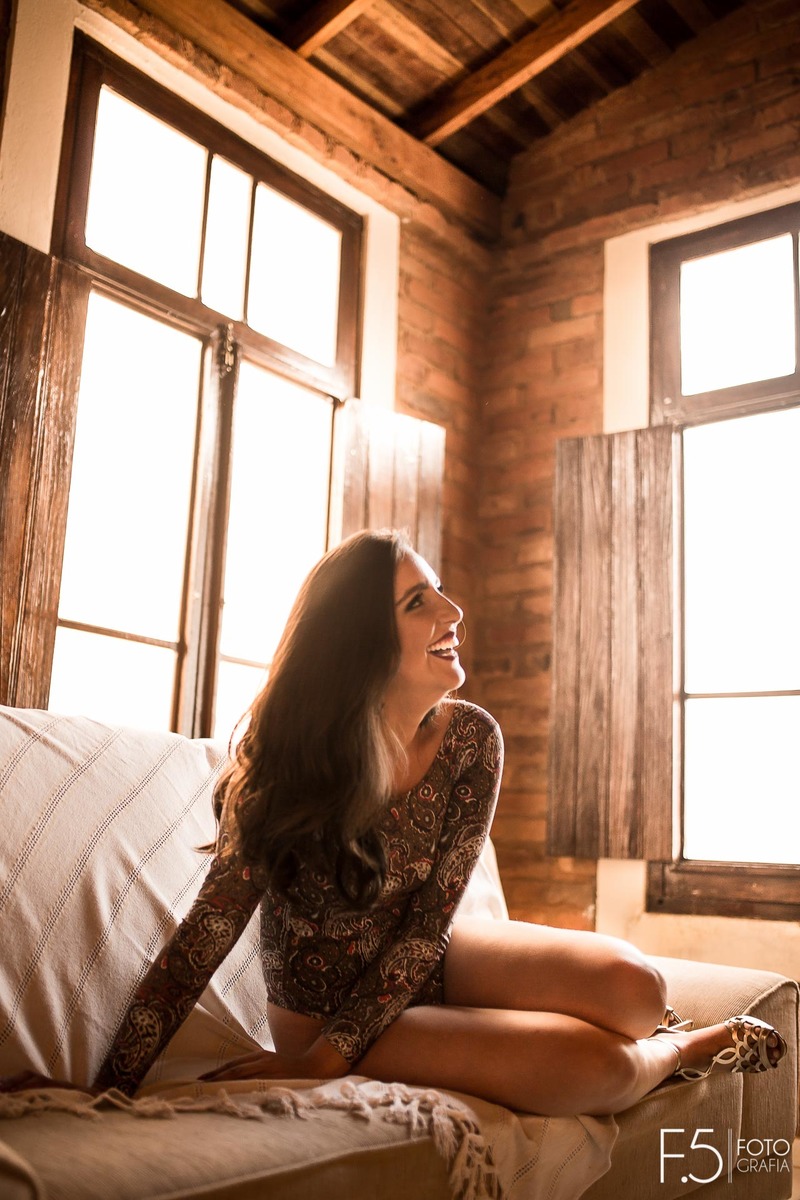 Jéssica, sentada no sofá sorrindo, em Muzambinho - MG.