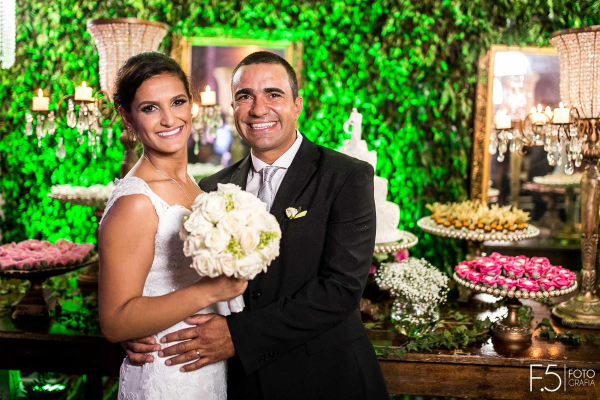 Festa dos noivos, Márcia e Renato, em frente a mesa do bolo e noiva segurando o buquê, em Muzambinho - MG.