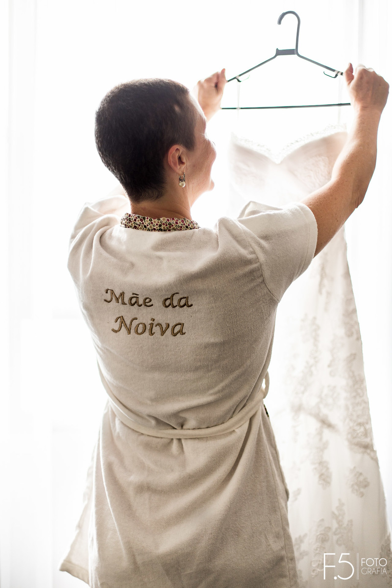 Making of da noiva, Eliza, sua mãe segurando o cabide com seu vestido, em Poços de Caldas - MG.