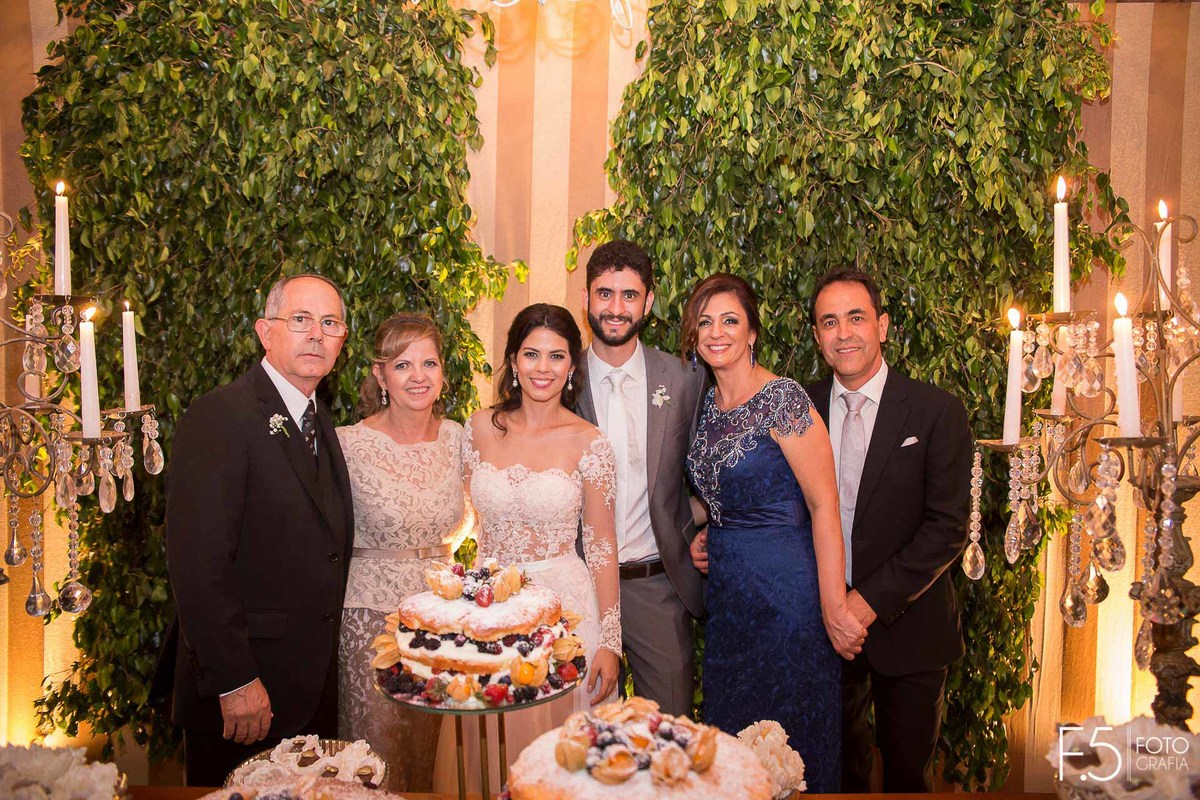 Noivos Mariana e Alan e seus pais na mesa do bolo, em Guaxupé - MG.