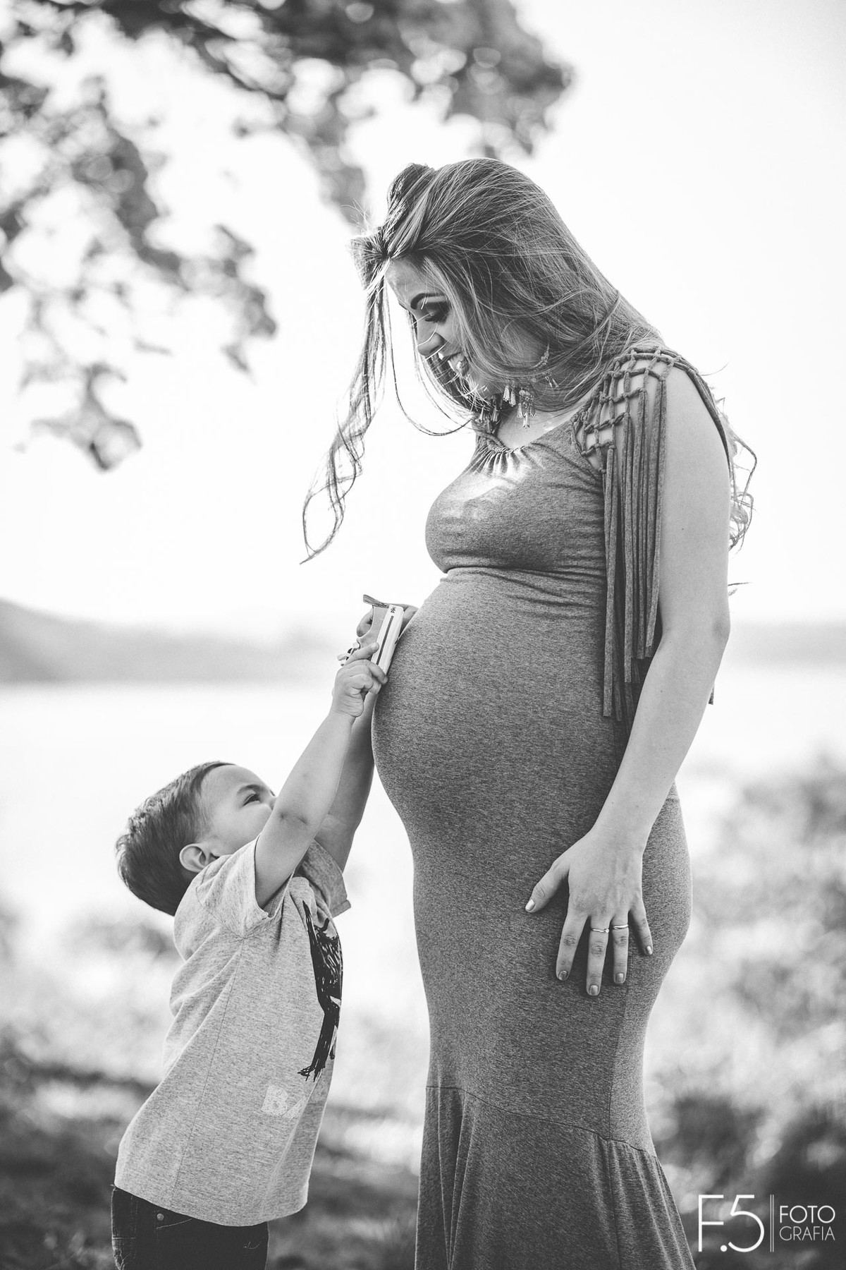 Filho da gestante colocando sapatinhos do bebê na sua barriga, Ensaio Gestante  - Areado MG