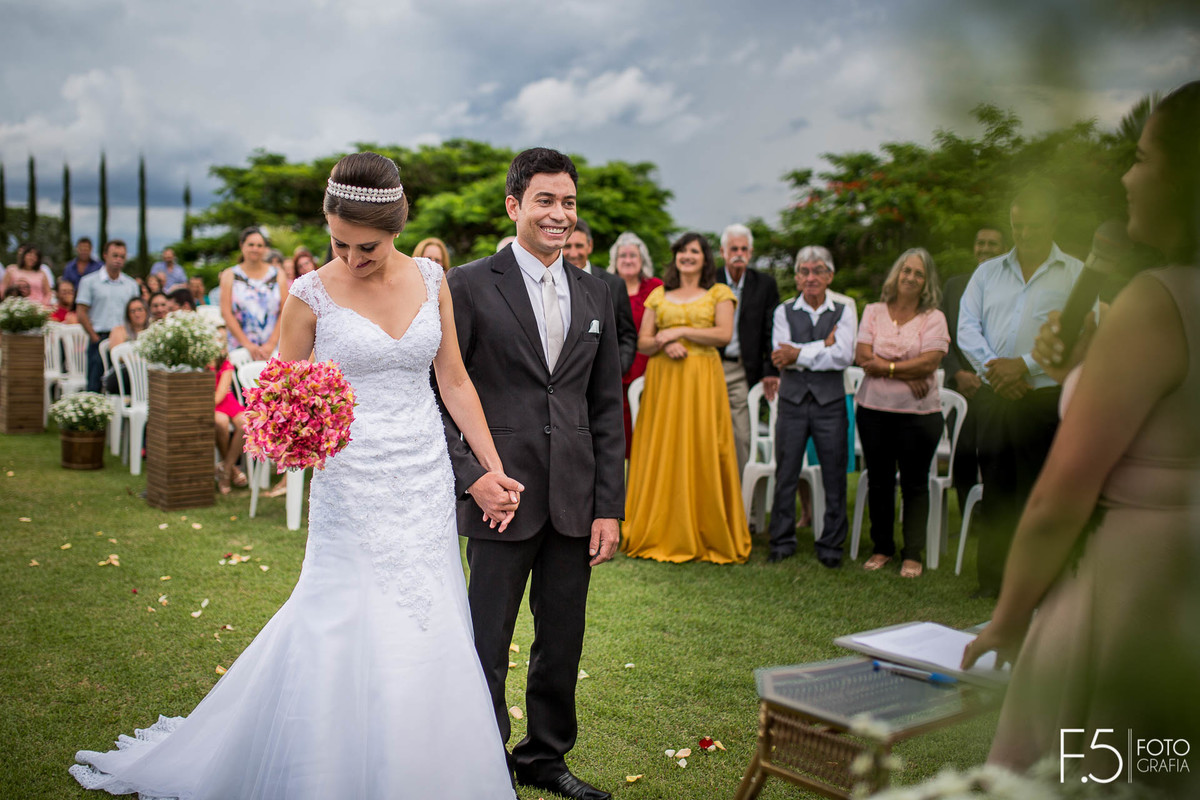 Casal de Noivos sorrindo meio a cerimônia ao ar livre, em Nova Resende - MG