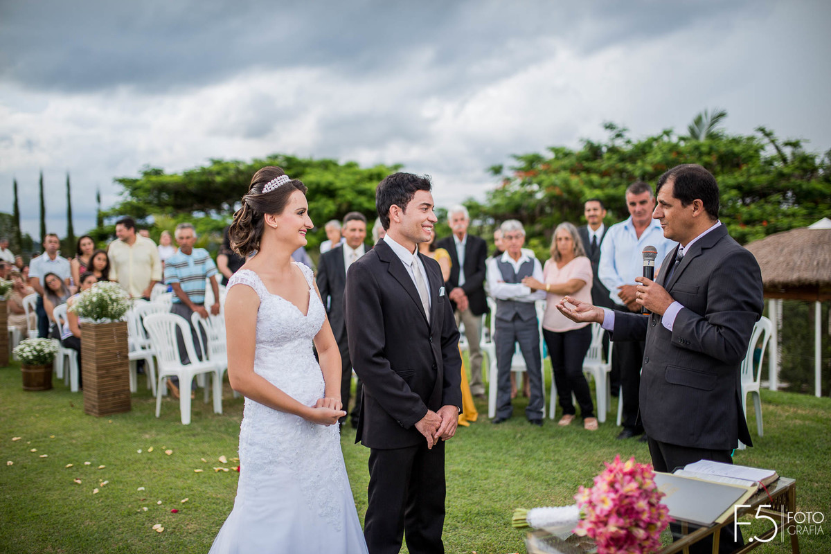 Casal de Noivos sorrindo meio a cerimônia ao ar livre, em Nova Resende - MG