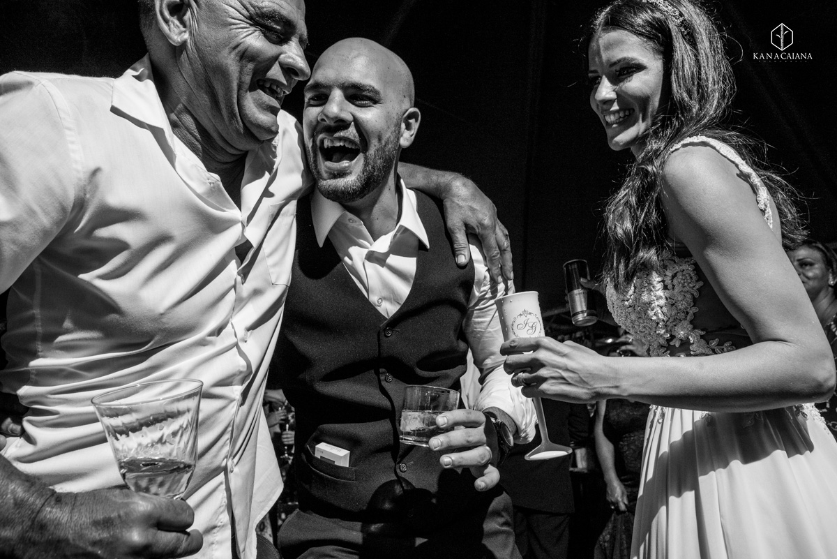 noivo abraça seu sogro e noiva observa durante sua festa de casamento