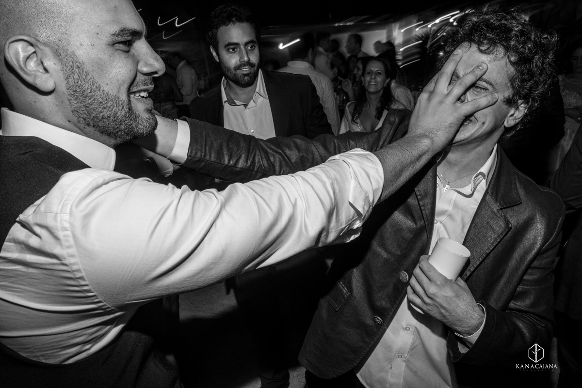 noivo coloca a mão no rosto ou cara de seu amigo durante festa de casamento