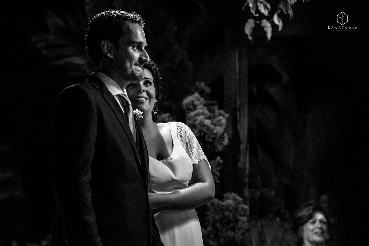 noiva sorrindo observa seu noivo emocionado e chorando durante a cerimonia do seu casamento no sítio casuarinas em Vargem Grande no rio de janeiro rj