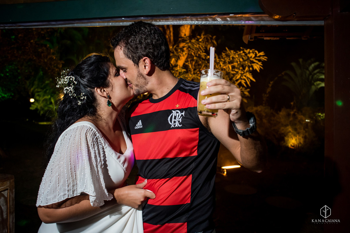 noivos se beijam apaixonados e noiva dá beliscão na barriga do noivo com a camisa do flamengo durante festa de casamento no sítio casuarinas em Vargem Grande no rio de janeiro rj