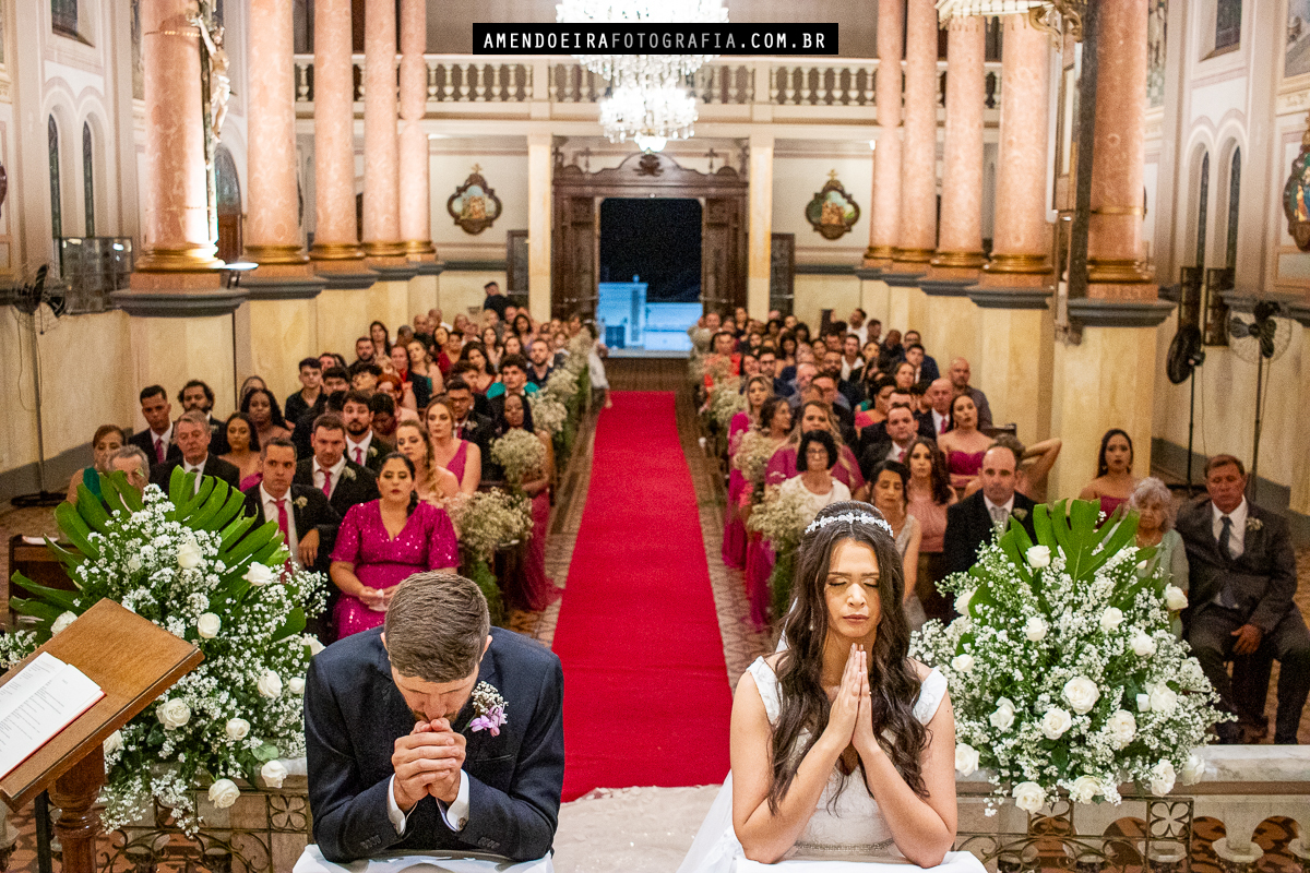 noivos oram e rezam durante omilia na cerimonia religiosa de casamento na igreja matriz de Bocaina no interior de são paulo e fotografo faz uma foto incrível