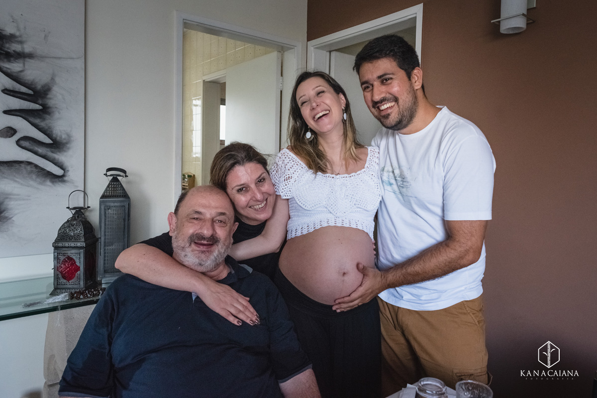 filha grávida seu marido e seus pais abraçados e sorrindo durante ensaio de fotos de gestante em São Paulo sp