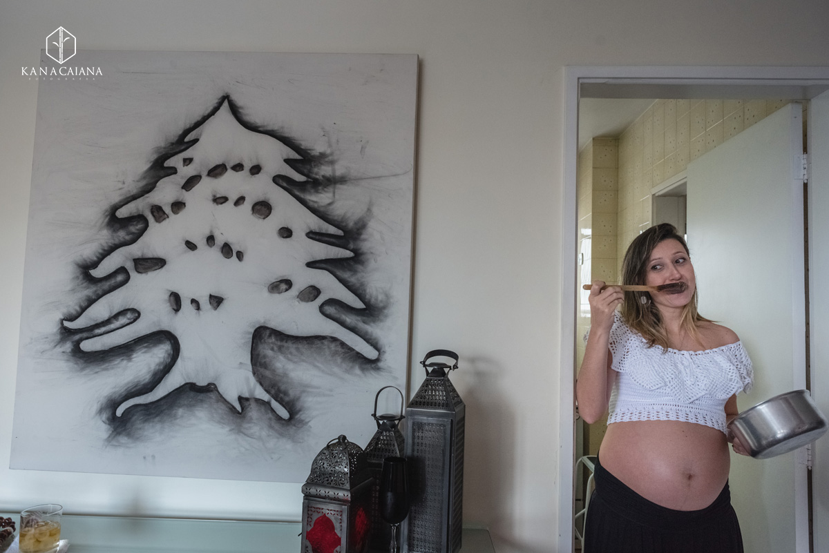 mulher grávida comendo brigadeiro na colher de pau durante ensaio de fotos de gestante em São Paulo sp
