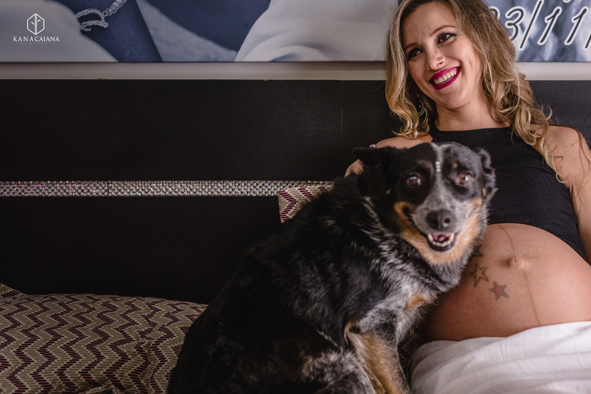 mulher grávida sorri e faz carinho em seu cachorro durante ensaio de fotos de gestante na cidade de lençóis paulista no interior de São Paulo sp