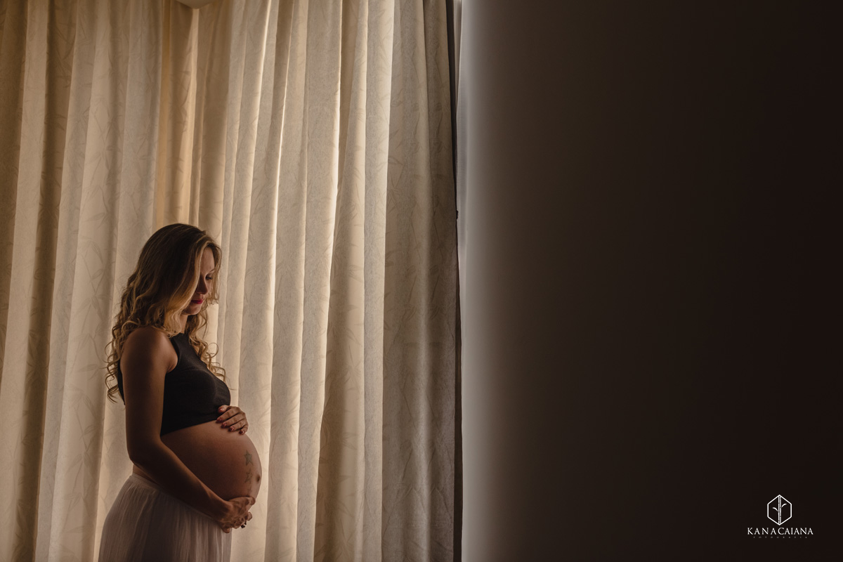 Mulher grávida acaricia barriga e sorri durante ensaio de fotos de gestante na cidade de lençóis paulista no interior de São Paulo sp