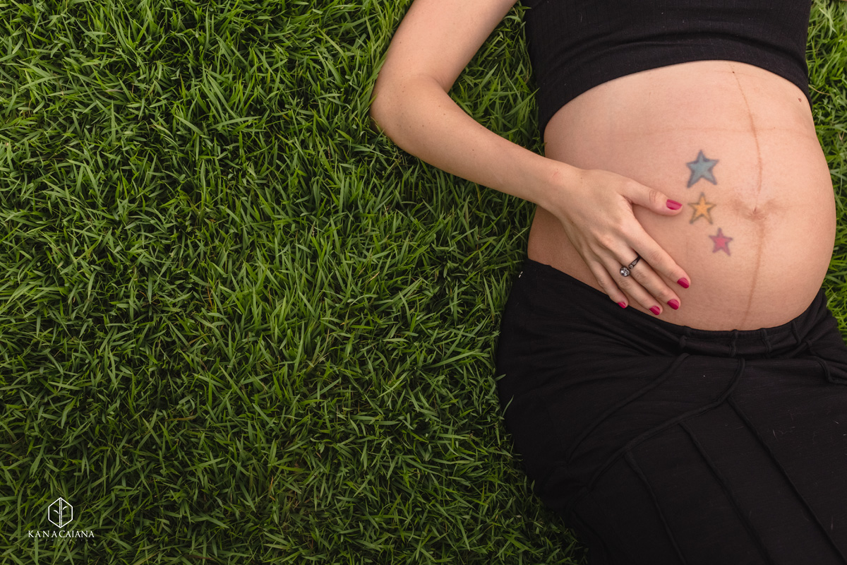 barriga de mulher grávida deitada na grama durante ensaio de fotos de gestante na cidade de lençóis paulista no interior de São Paulo sp