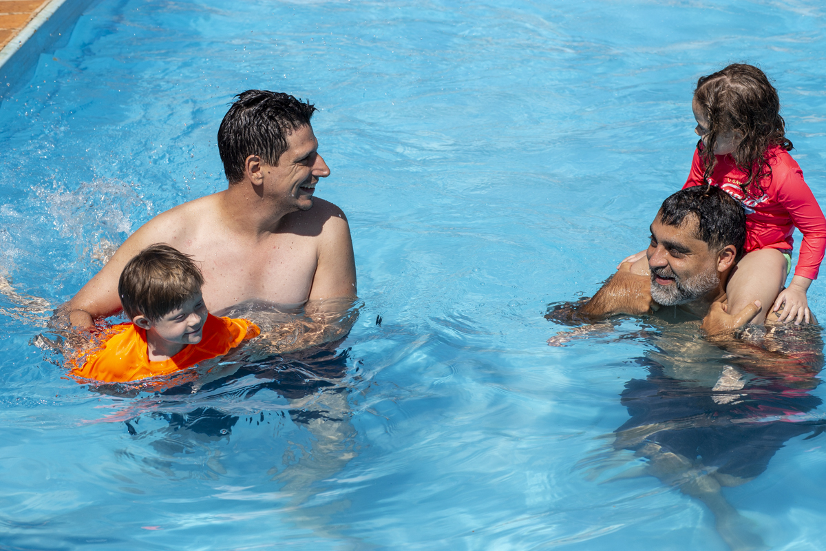 fotografo de casamento no campo em brotas registra momento espontâneo do noivo e padrinho brincando com crianças na piscina no pre casamento em brotas sp